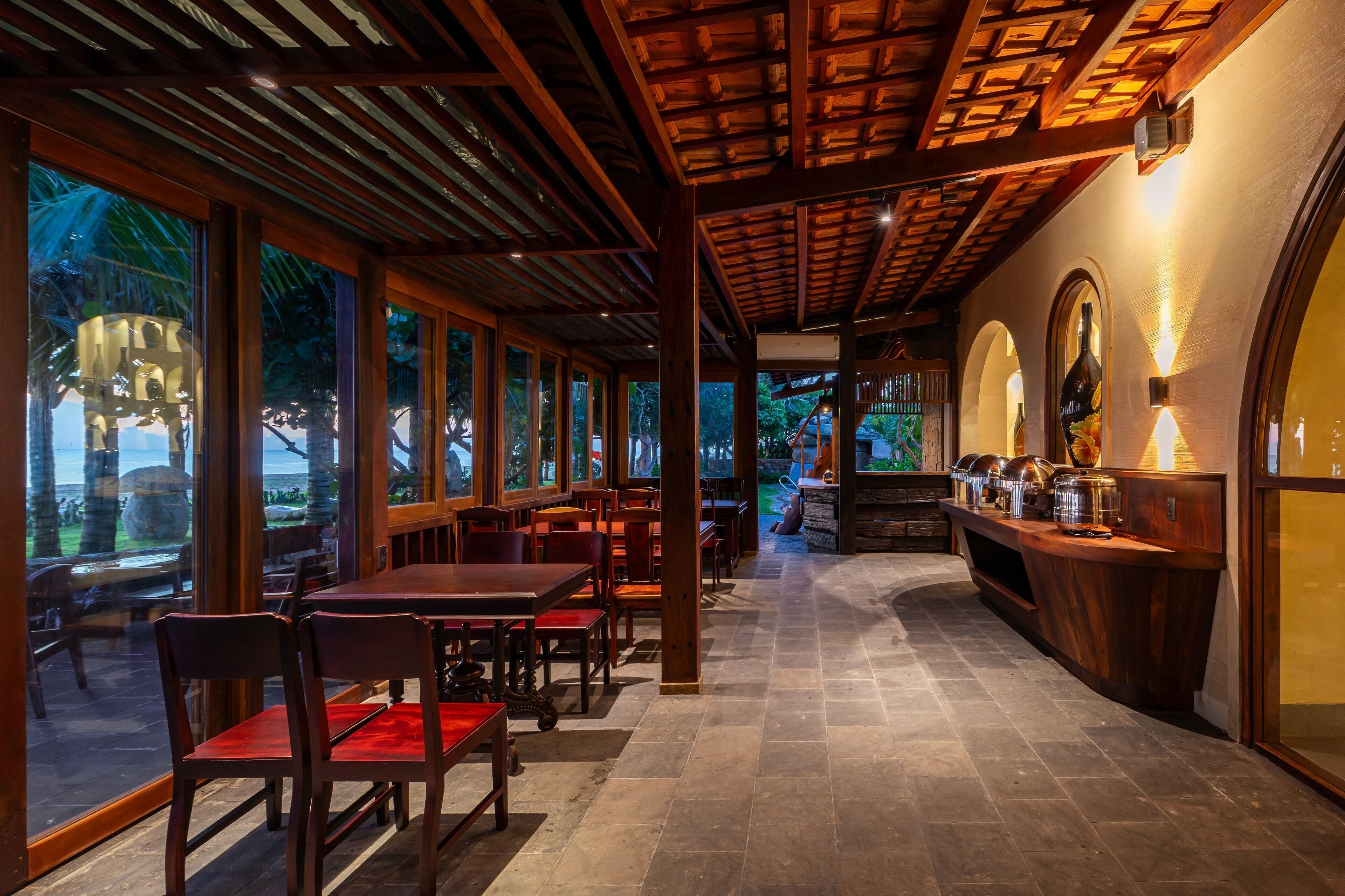 A restaurant with wooden tables and chairs, large windows, and a stone fireplace.