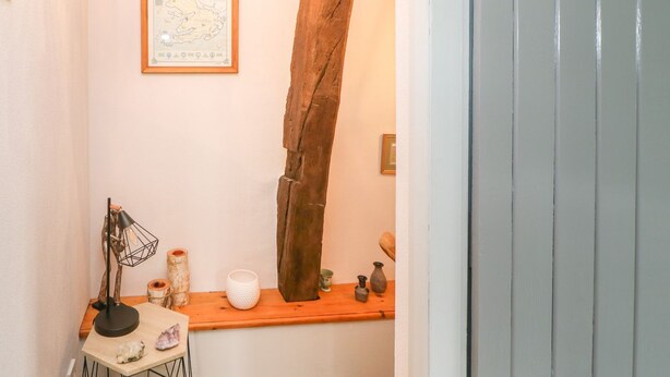 A small, cozy room with a wooden beam, a map on the wall, and a shelf with decorative items.