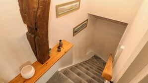 A staircase with a wooden handrail and a wall-mounted shelf with a vase and a bowl.