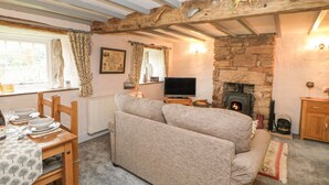 A cozy living room with a stone fireplace, wooden beams, a sofa, and a television.
