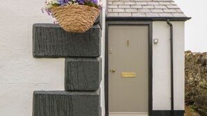 A building entrance with a white door, a black mailbox, and a stone wall.
