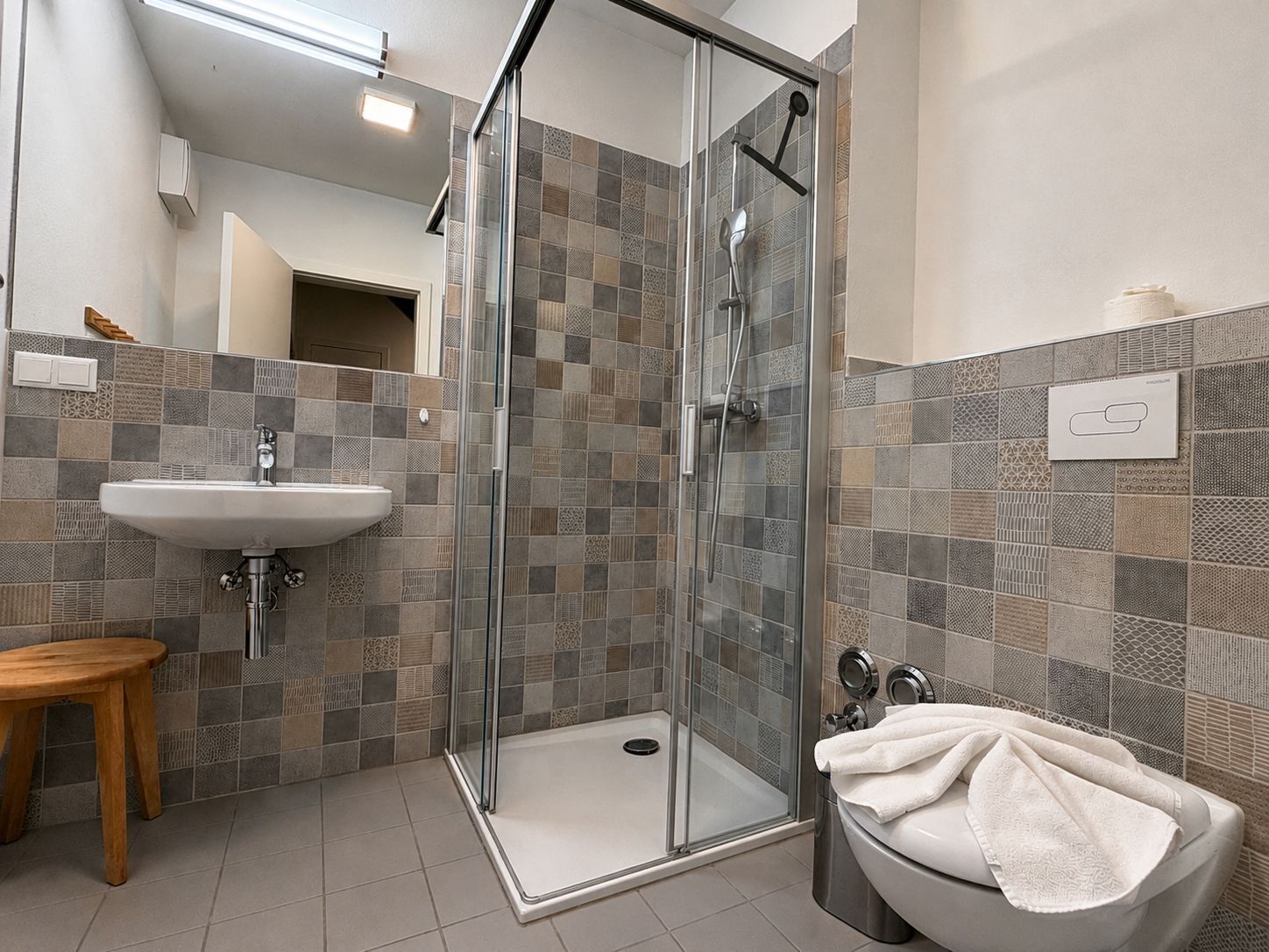 Een moderne badkamer met een douchecabine van glas, een wastafel en een toilet.