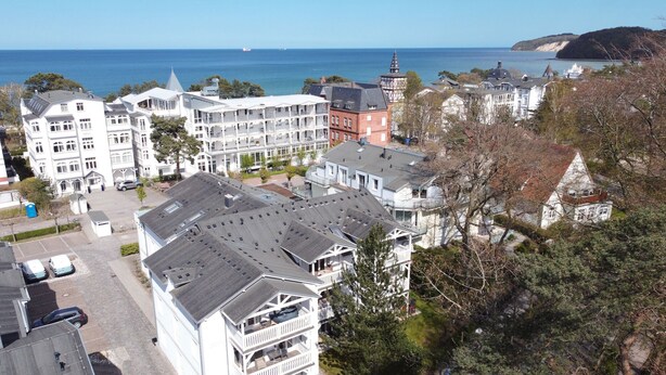A coastal town with a mix of residential and commercial buildings, including a prominent white building with multiple balconies and a red brick structure with a tower.