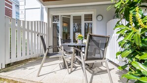 A patio with a table and chairs, a wooden ceiling, and a white fence.