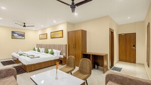 A hotel room with a bed, two chairs, a desk, a coffee machine, and a ceiling fan. - Hotel Veda Inn By Blue Lotus (Rishikesh)