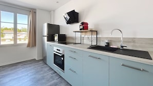 A modern kitchen with a built-in oven, a sink, and a flat-screen TV mounted on the wall.