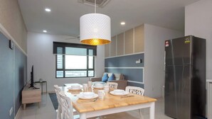 A modern kitchen with a dining table set for four, a refrigerator, and a pendant light. - Spacious 2BR Suasana, near CIQ JB Sentral (Johor Bahru)