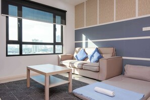 A modern room with a sofa, a table, and a view of a cityscape through a large window.