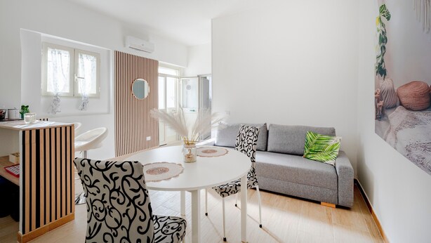 Ein modernes Wohnzimmer mit einem runden Tisch, einem grauen Sofa und einer weißen Trennwand.