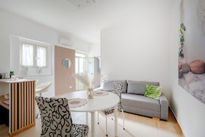 A modern living room with a round table, a grey sofa, and a white partition.