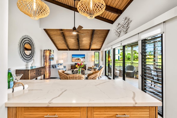A modern kitchen with a marble countertop, wooden cabinets, and a dining area with wicker furniture.