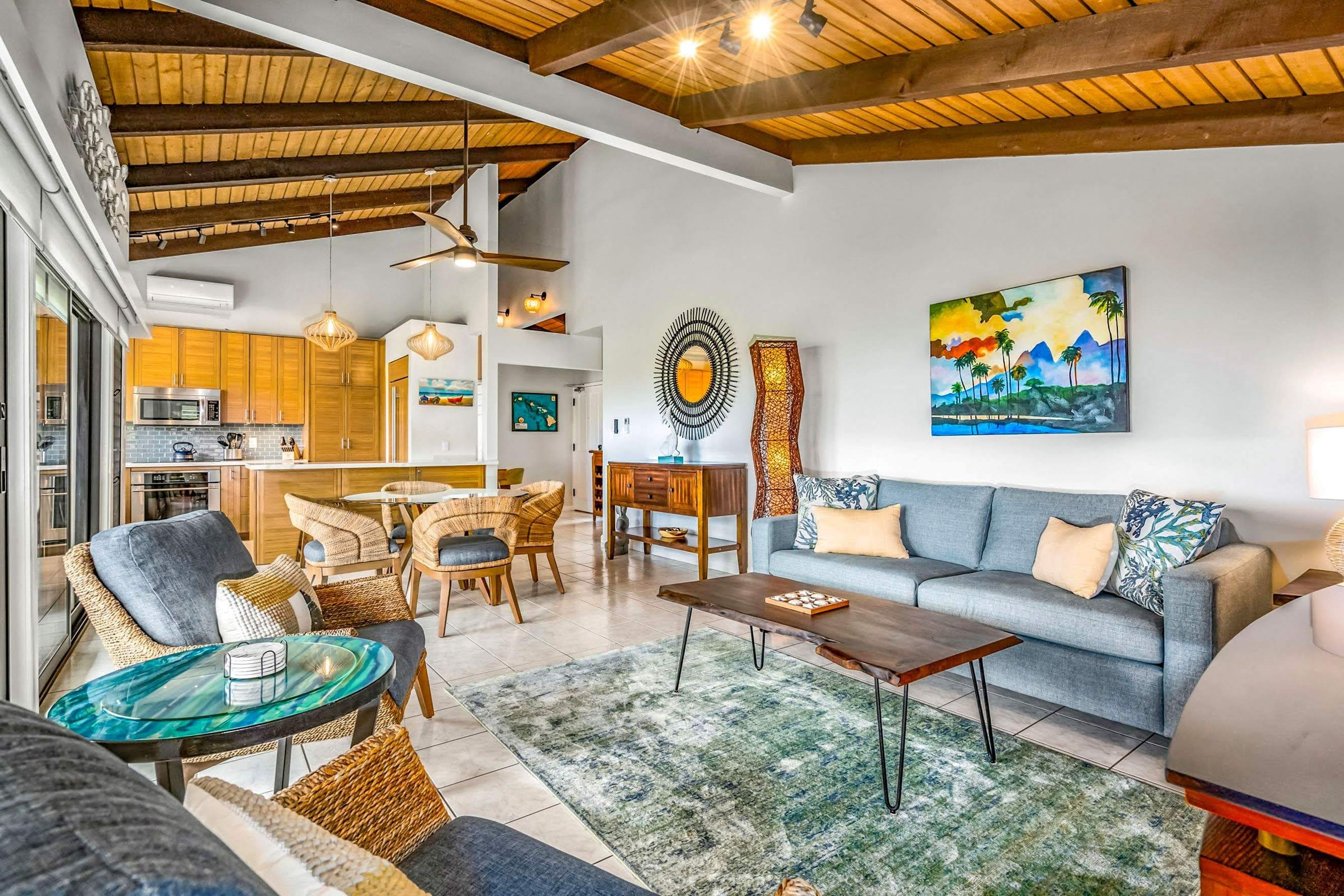 A modern living room with a sofa, chairs, a coffee table, and a dining area with a kitchen in the background.