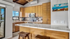 Une cuisine moderne avec des meubles en bois, un grand îlot central et des luminaires suspendus.