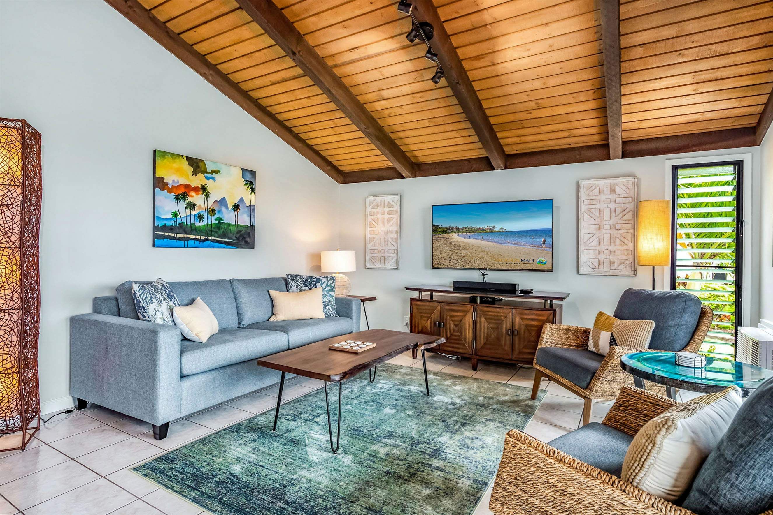 Una sala de estar con sofá, mesa de centro, sillones, televisión y obras de arte en las paredes.