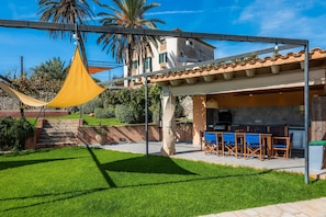A patio with a barbecue area, outdoor seating, and a stone wall. - Ground Floor Room with Shared Pool, Wi-Fi, and Air Conditioning (Artá)