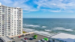 A high-rise hotel with a parking lot and ocean view. - Azure Tides Oceanfront (Daytona Beach)