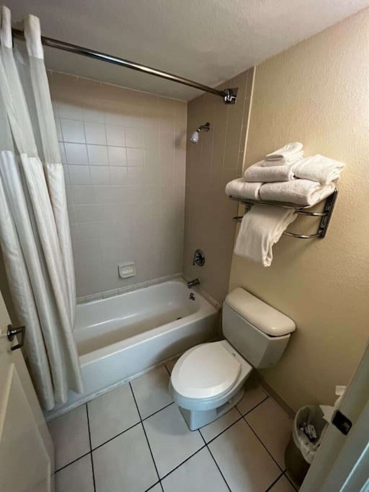 Un baño con bañera, inodoro y toallero con toallas dobladas.