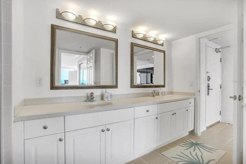 Une salle de bain avec deux grands miroirs, un lavabo et une douche.