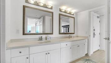Une salle de bain avec deux grands miroirs, un lavabo et une douche.