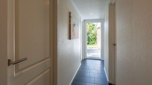 A narrow hallway with a door on the left and a door at the end.