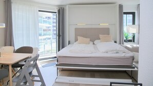 Ein modernes Hotelzimmer mit Bett, Schreibtisch und Blick auf die Stadt.