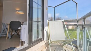 Ein Zimmer mit großem Fenster, einem Sessel, einem Tisch und einer Pendelleuchte.
