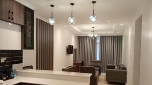 A modern kitchen with a built-in refrigerator, a dining area with a sofa, and a living room with a TV. - Highland Rhinor (Eldoret)