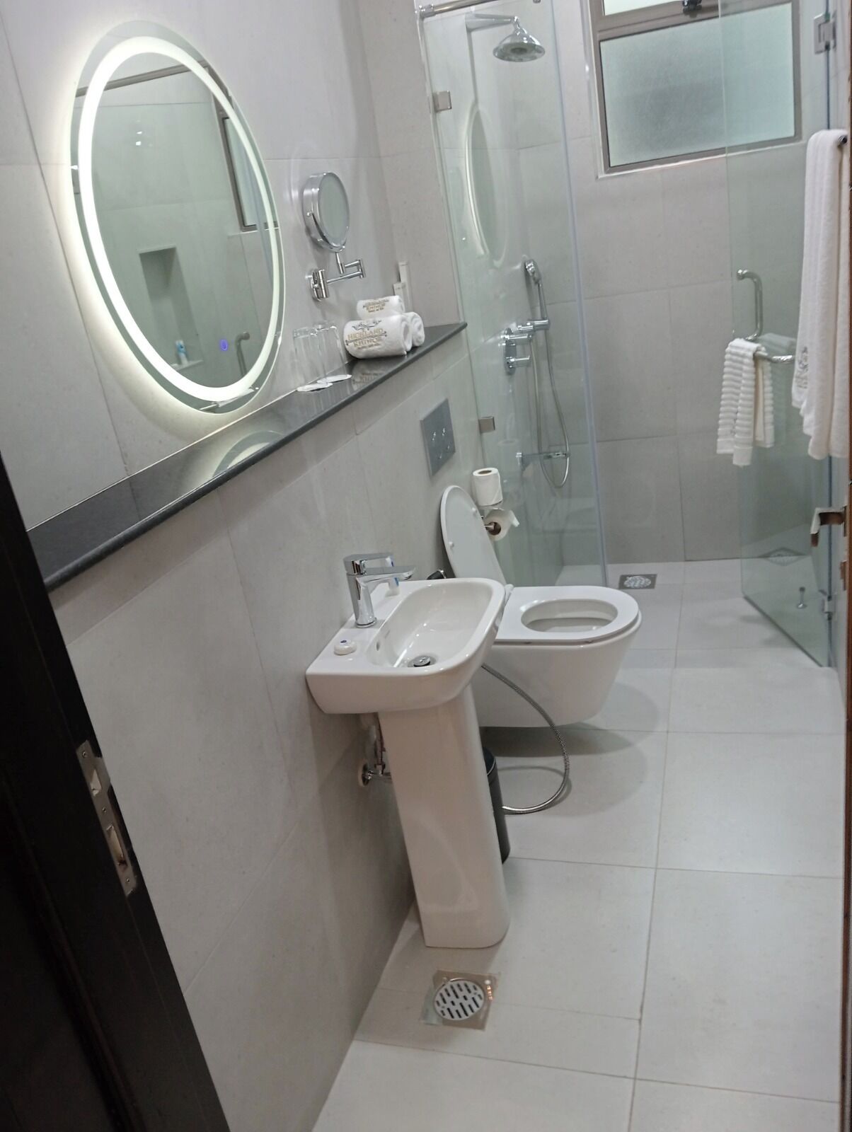 A modern bathroom with a toilet, sink, and glass shower enclosure.