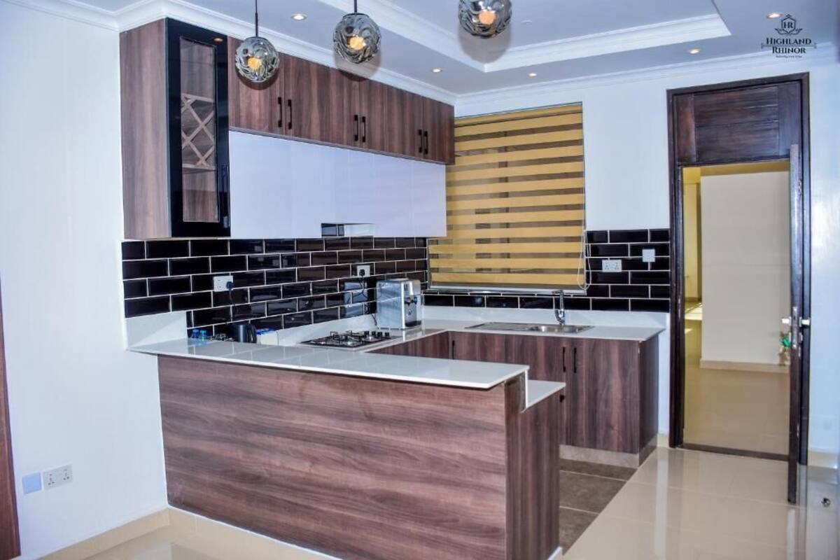 A modern kitchen with dark wood cabinets, a black and white tiled backsplash, and a central island.