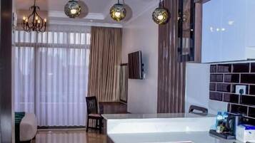 A modern kitchen with a built-in refrigerator, a dining area with a table and chairs, and a chandelier.
