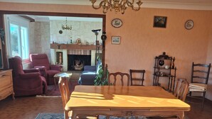 Un coin repas avec une table et des chaises en bois, une cheminée et un lustre.