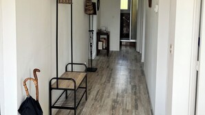Un couloir doté d’un plancher en bois, d’un ventilateur de plafond noir, d’un lampadaire et d’une canne appuyée contre le mur.