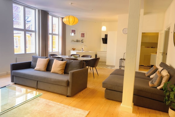 A living room with two sofas, a glass coffee table, and a dining area with a table and chairs.