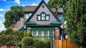 A two-story house with a gabled roof, a front porch, and a wooden fence. - Retreat on Bardstown Road | Yard • Great Location (Louisville)