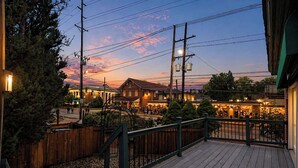 A wooden deck with a railing, overlooking a town with buildings and a sunset. - Retreat on Bardstown Road | Yard • Great Location (Louisville)