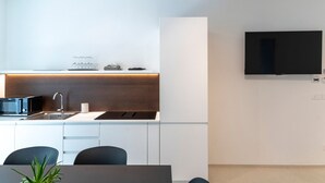 Une cuisine moderne équipée d’un four à micro-ondes encastré, d’un évier et d’un plan de travail. Un téléviseur à écran plat est fixé au mur, au-dessus du plan de travail.