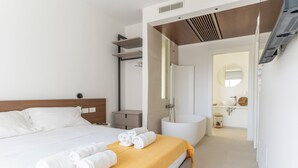 Une chambre d’hôtel moderne dotée d’un grand lit, d’une salle de bain avec baignoire et d’un petit coin salon.
