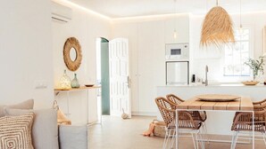 A modern living room with a wooden coffee table, a sofa, and a dining area with wicker chairs. - Arenal Apartment ONLY ADULTS (Arenal d'en Castell)
