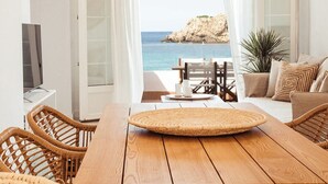A modern room with a wooden dining table, wicker chairs, and a view of the sea. - Arenal Apartment ONLY ADULTS (Arenal d'en Castell)