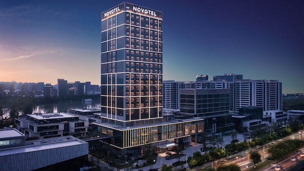 Um hotel moderno com um letreiro chamativo da 'NOVOTEL', apresentando uma grade de janelas e fachada de vidro.
