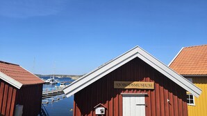 Un puerto con edificios de madera, incluyendo un museo que dice 'Sjöbodsmuseum'. Barcos amarrados al fondo.