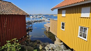 Un puerto con barcos, un muelle de madera y dos edificios con fachadas rojas y amarillas.
