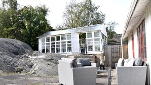 Una casa moderna con amplios ventanales, mobiliario para exterior y un camino de piedra.