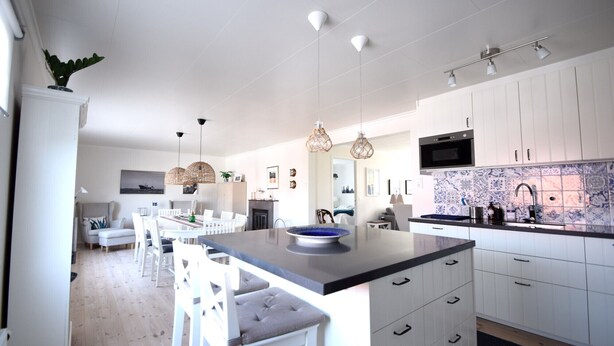 Una cocina moderna con armarios blancos, encimera negra e iluminación colgante.