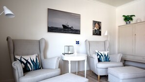 Una sala de estar moderna con dos sillones grises, una mesita de noche pequeña y blanca, y un mueble aparador grande.