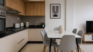 A modern kitchen with a dining area, featuring a marble table, grey chairs, and a black TV stand. - Spacieux 3 pieces a Kouba (Algiers)