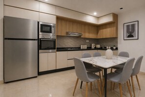 A modern kitchen with stainless steel appliances, a marble dining table, and grey chairs. - Spacieux 3 pieces a Kouba (Algiers)
