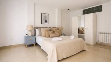 A bedroom with a bed, bedside tables, a wardrobe, and a radiator.