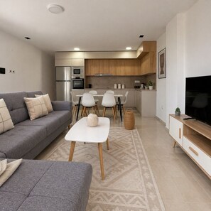 A modern living room with a grey sofa, a white coffee table, and a TV stand. - Spacieux 3 pieces a Kouba (Algiers)