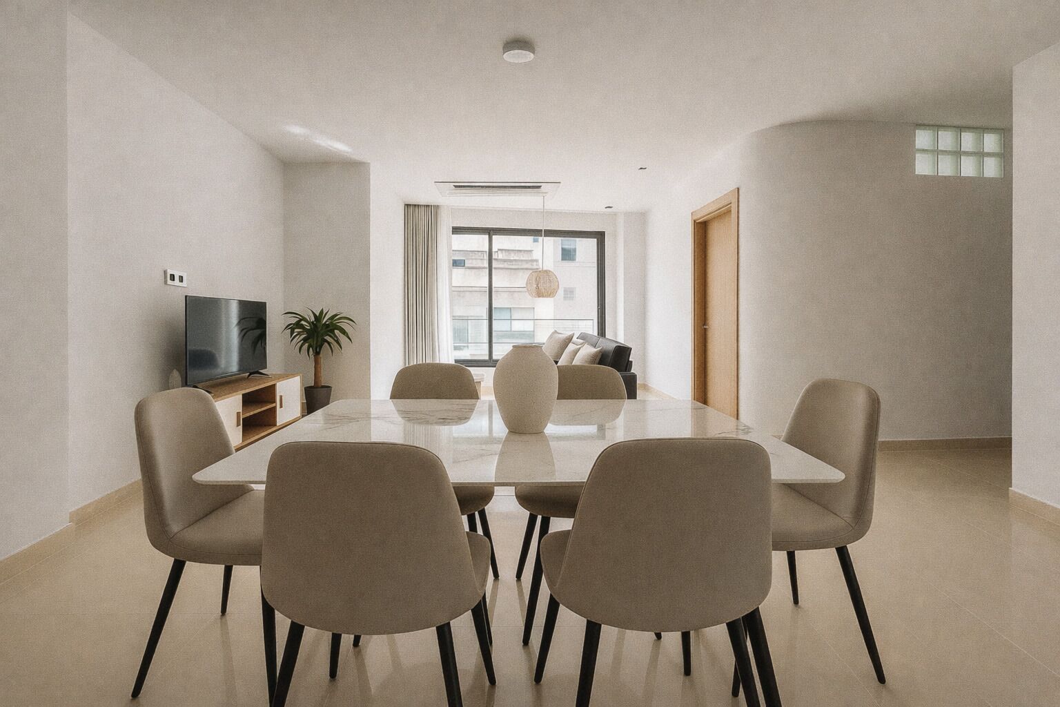 Un comedor moderno con una mesa rectangular, seis sillas, un televisor y una planta en maceta.